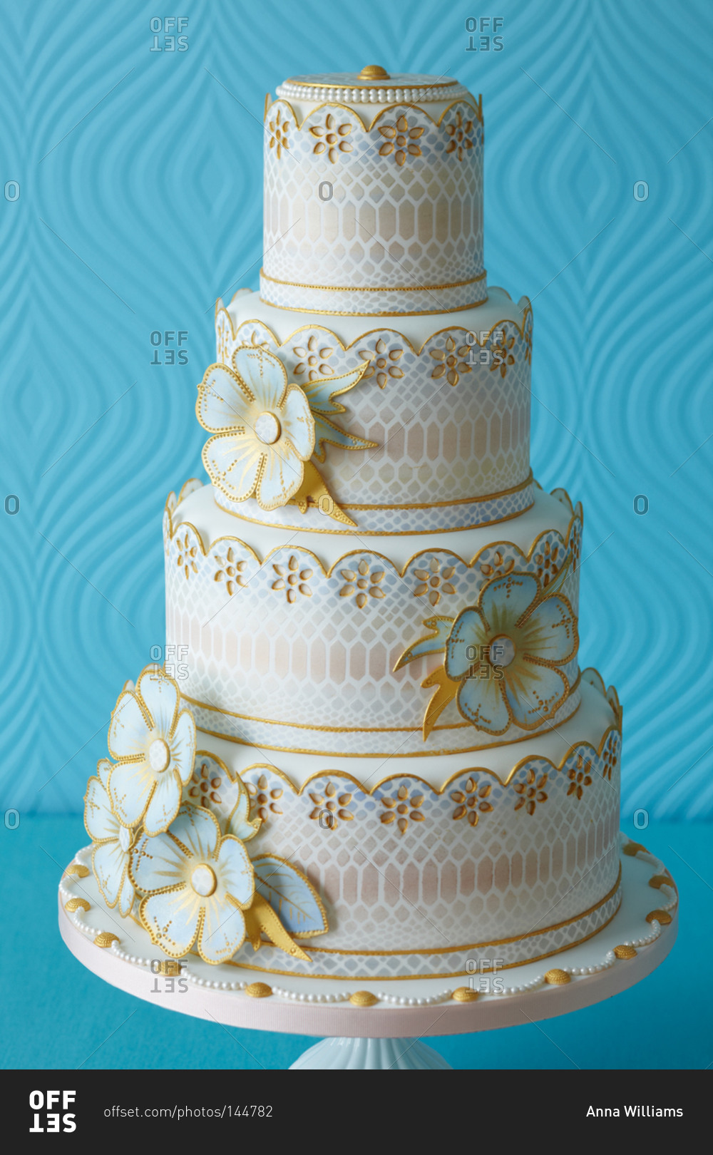 Flowers outlined in gold decorate a four-tiered cake