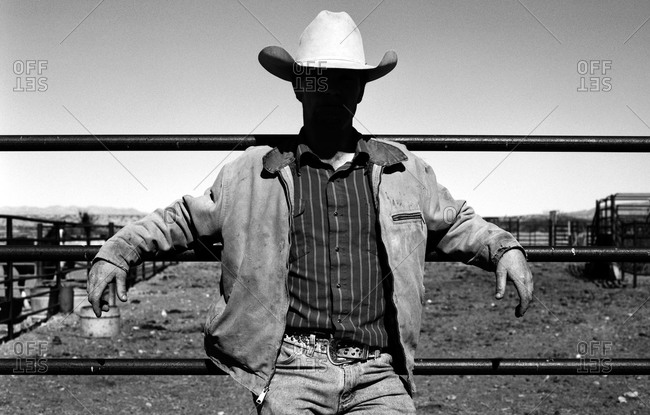 Cowboy resting on corral fence