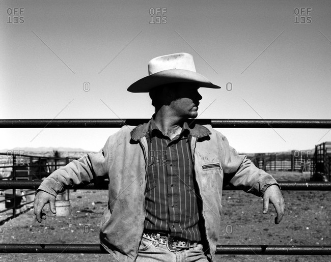 Cowboy leaning on corral fence