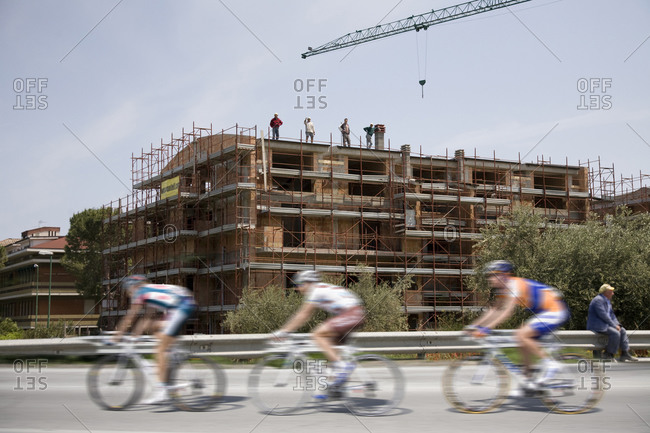 Cesenatico, Italy - May 20, 2010: Cyclists pass by a construction site, Giro d'Italia