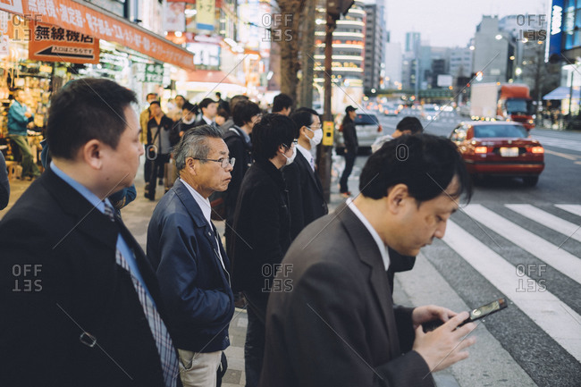 Tokyo, Japan - April 1, 2014: Men stand on a corner waiting to cross the street