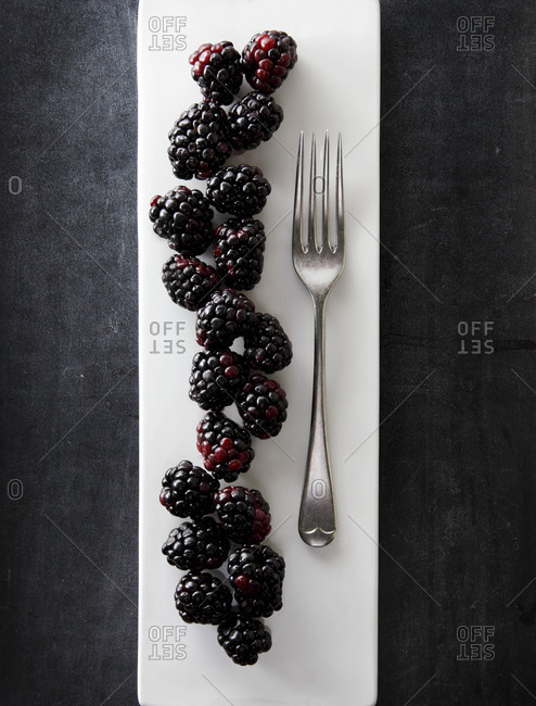 Blackberries line up next to a fork