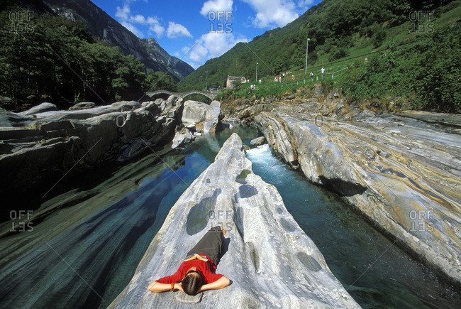 A woman reading and napping along the river in the Valle Verzasca, Lavartezzo, Ticino, Switzerland