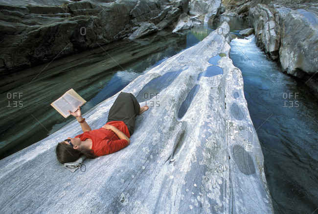A woman reading and napping along the river in the Valle Verzasca, Lavartezzo, Ticino, Switzerland