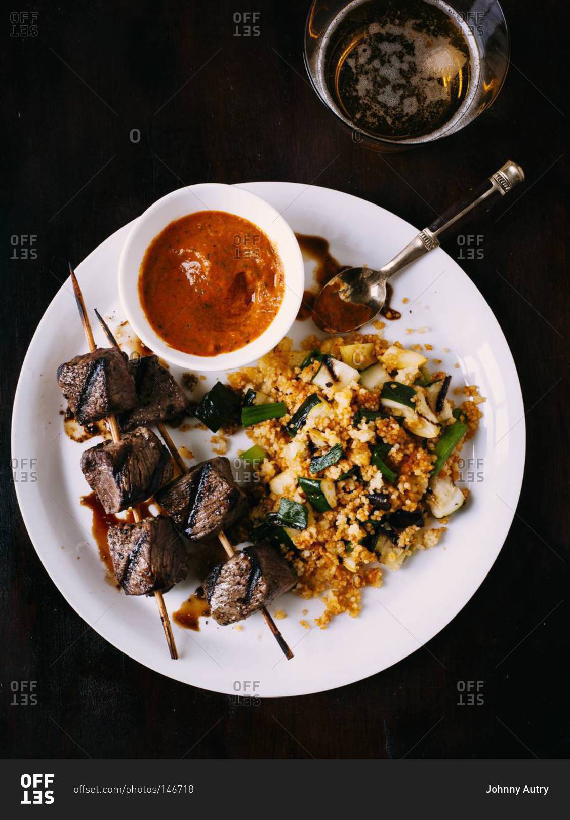 Grilled beef skewers with spicy dipping sauce, vegetable couscous seasoned with spices