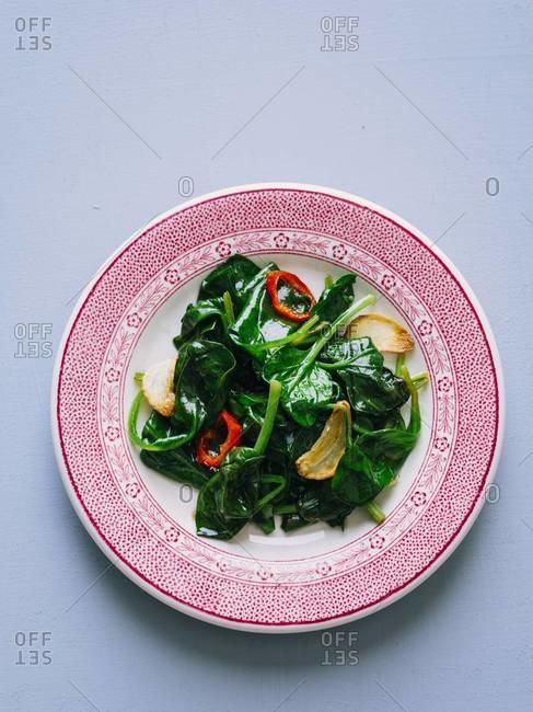 Studio shot of sauteed spinach with garlic chips and chili