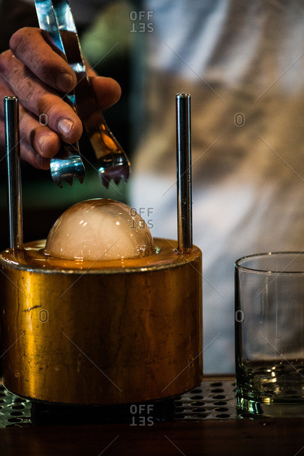 Man preparing ice sphere for cocktail