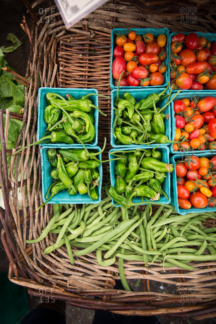 Peppers, green beans and tomatoes in rustic basket at the farmers market