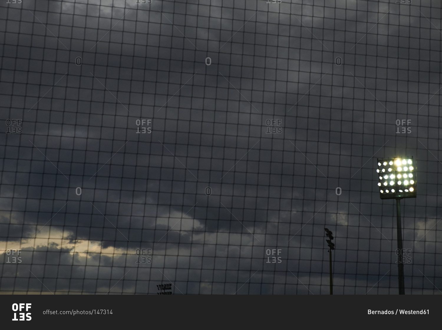 Football net in front of flood light and dark clouded sky