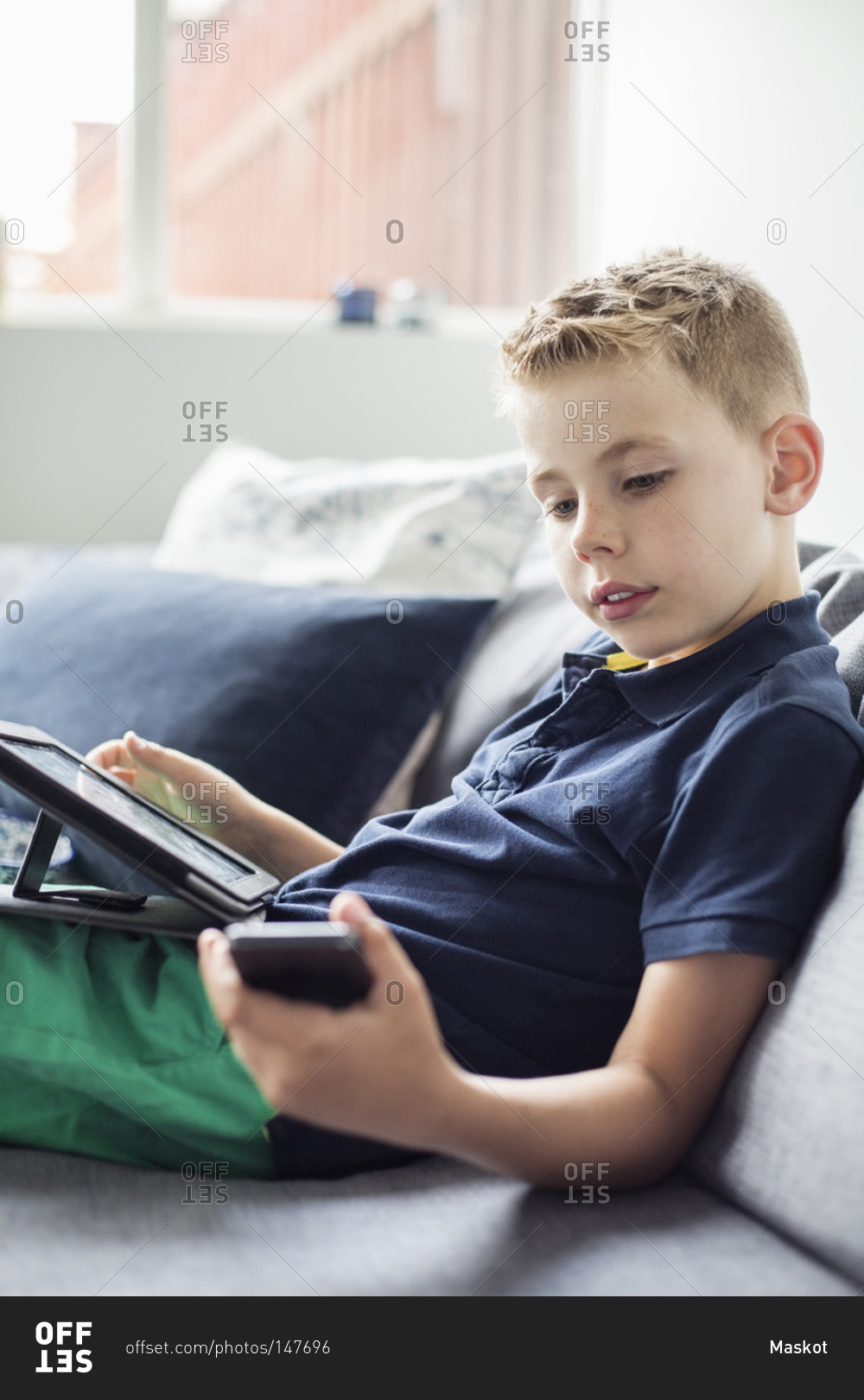 Boy using technologies on sofa at home