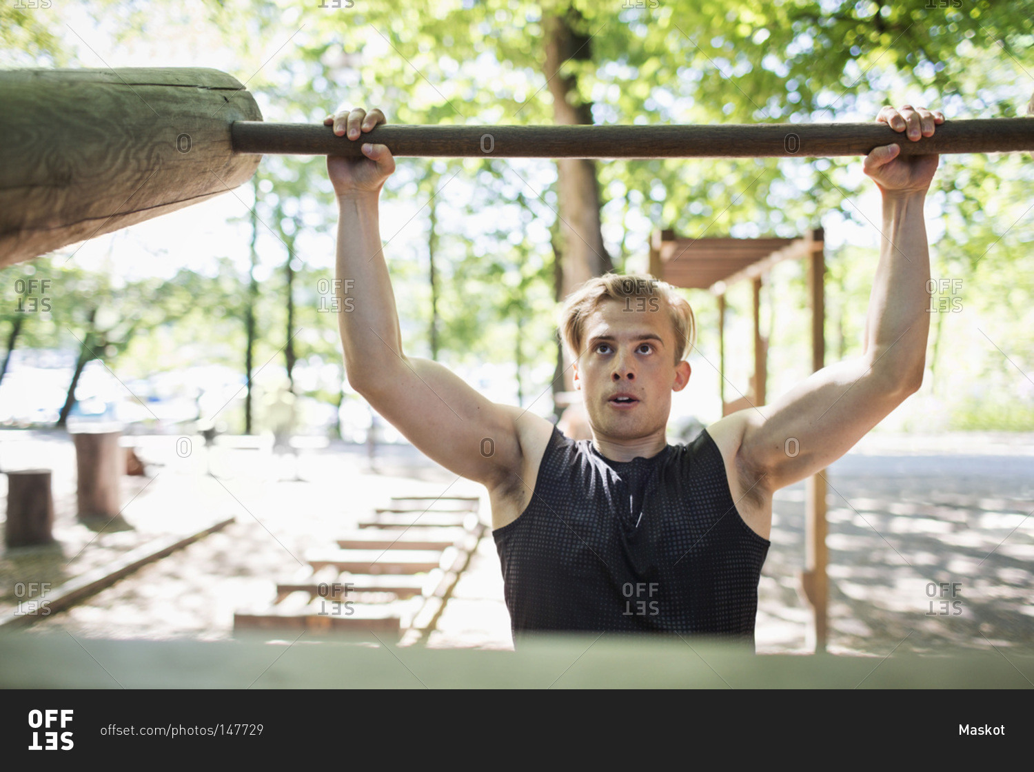 Determined man lifting wooden bar at outdoor health club