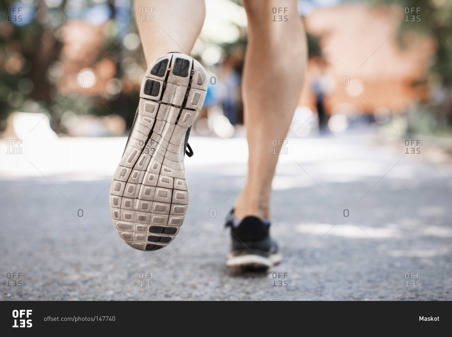 Low section of woman in sports shoes running on park street