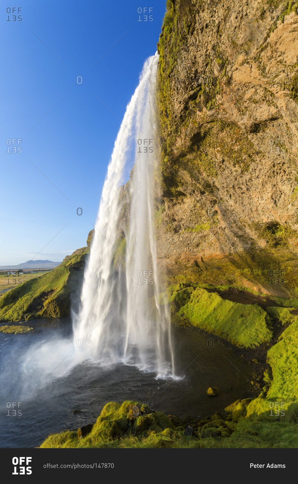 Rock overhang and Seljalandsfoss waterfall in Iceland stock photo - OFFSET