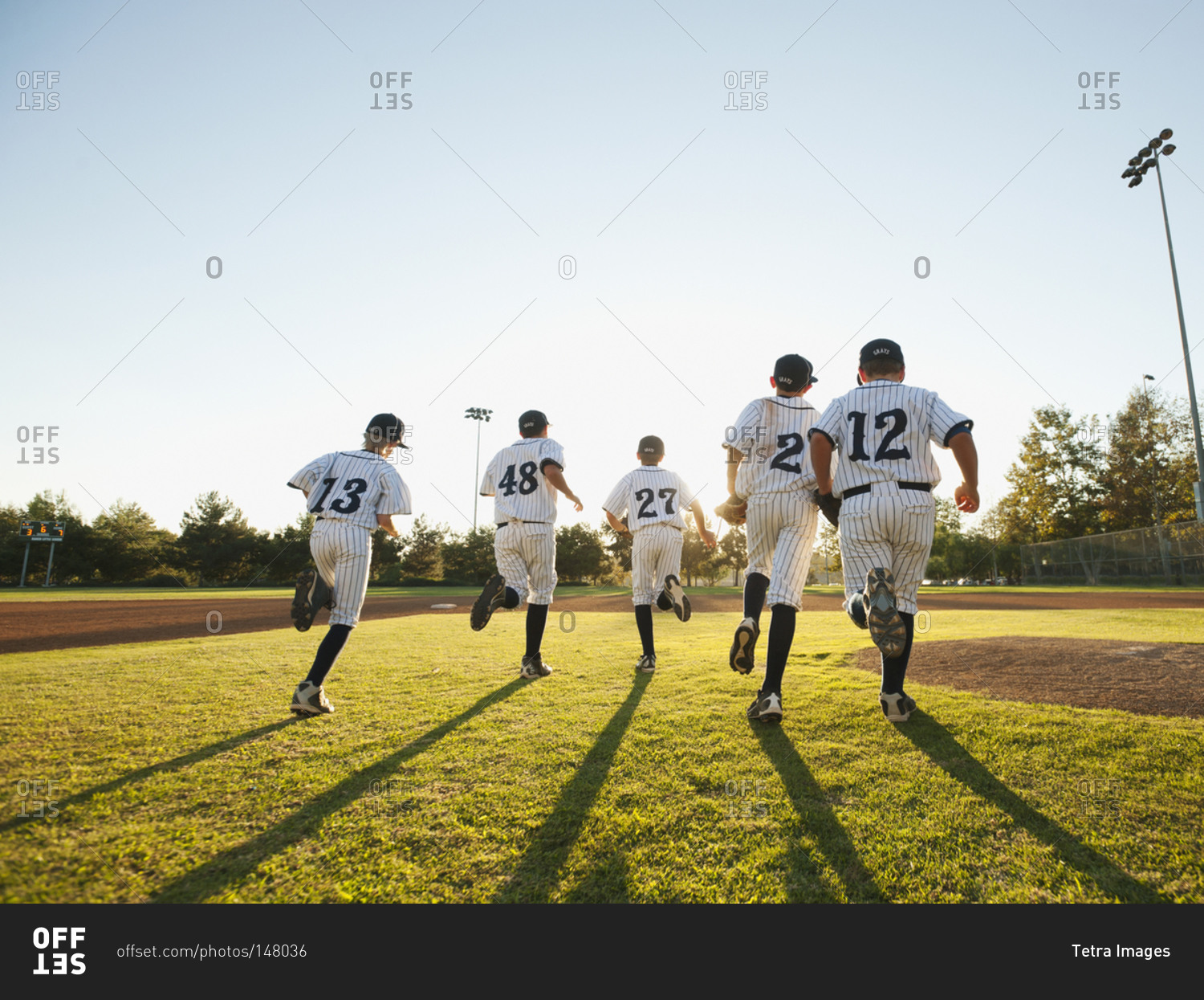 Baseball players (10-11) running on baseball diamond