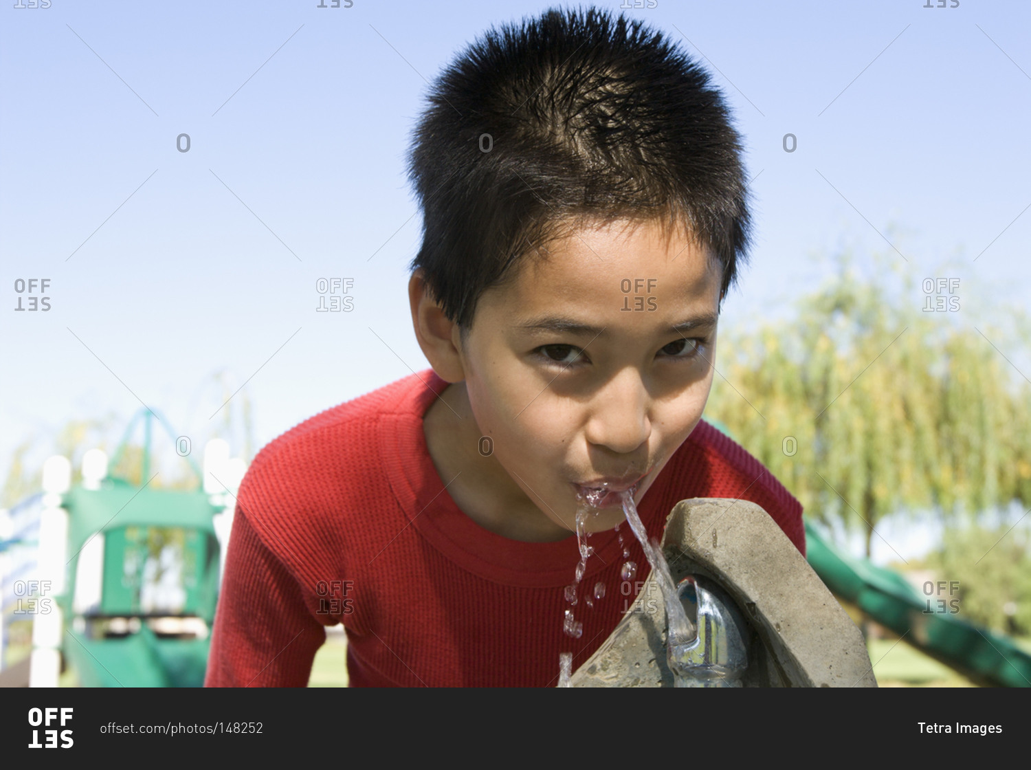 Boy (12-13) drinking from a water fountain