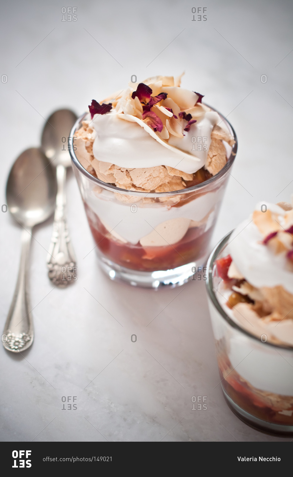 Two portions of a creamy dessert of coconut, crumbly meringue and rhubarb with rose petals