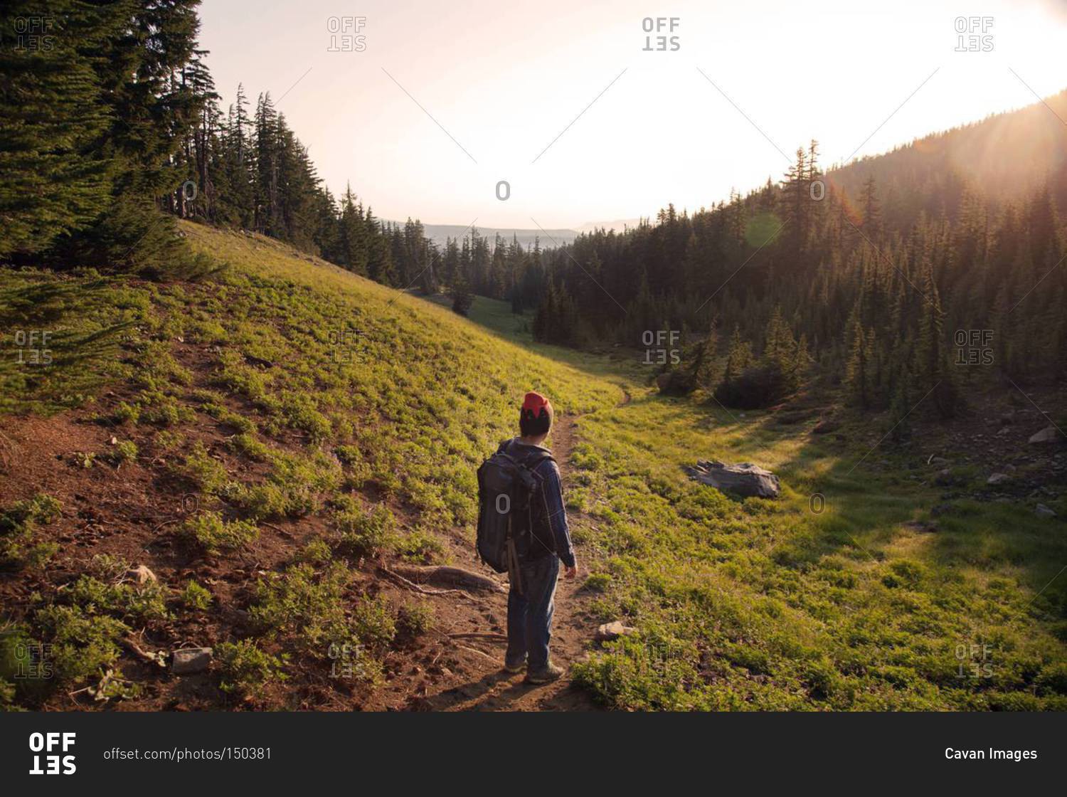 Hiker looking at setting sun over mountain valley, central Oregon