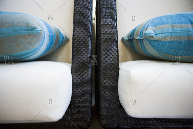 Detail of two contemporary arm chairs with blue throw pillows