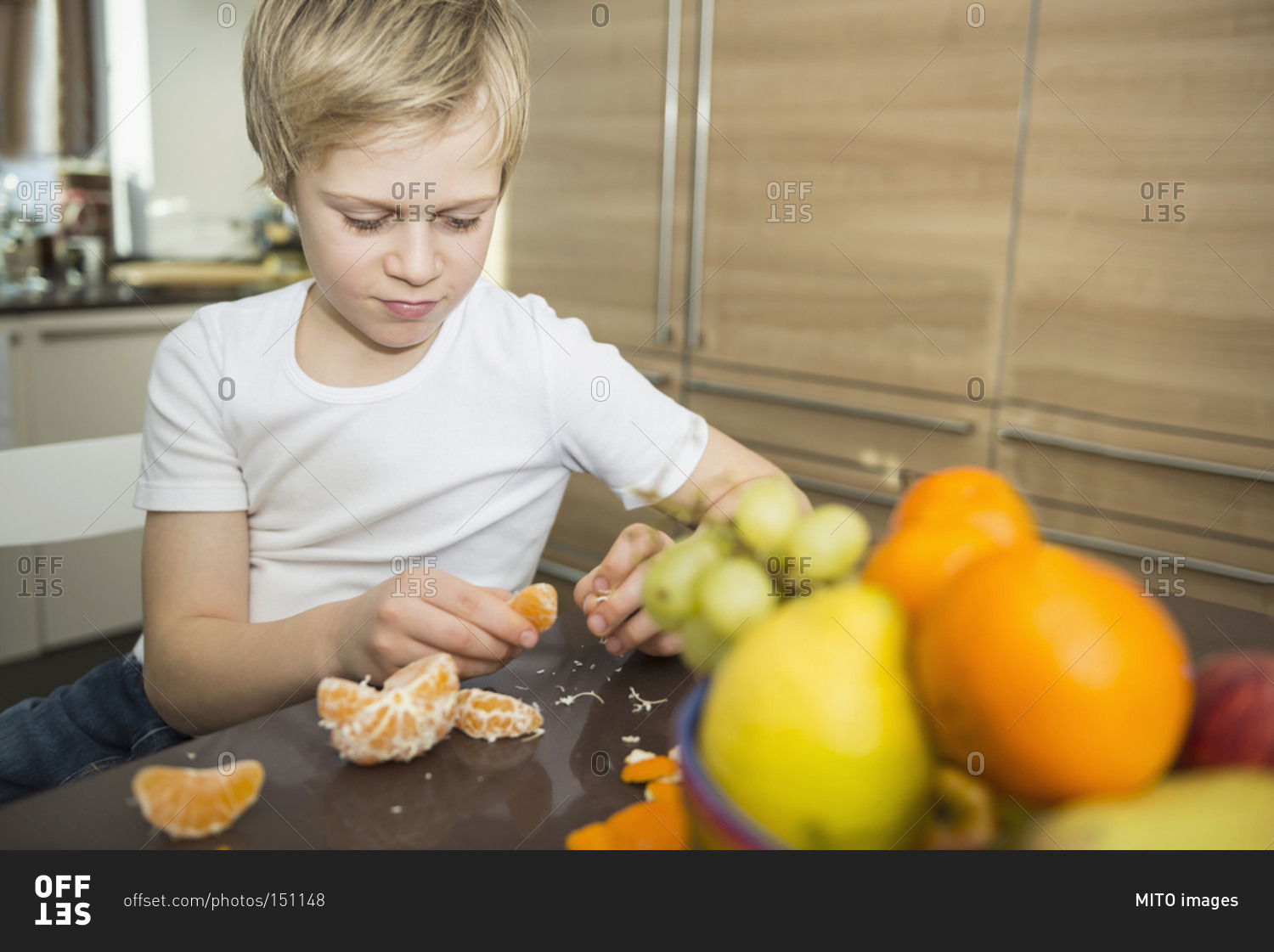 Portrait of boy at home peeling a tangarine