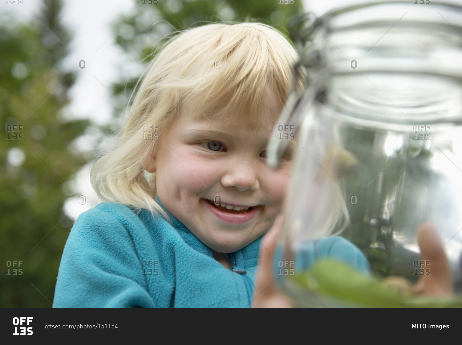Small blonde girl collecting snails in jam-jar