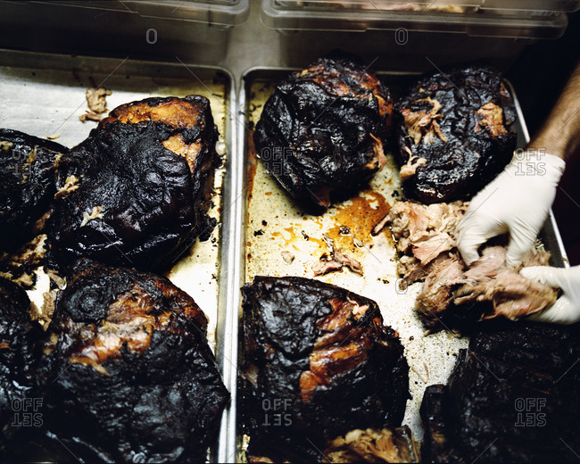 Person preparing pulled pork from smoked pork shoulder