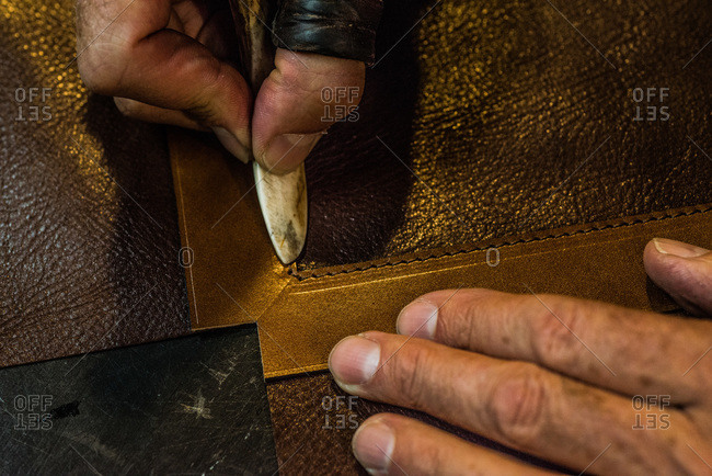Artisan pressing a craft tool on a piece leather