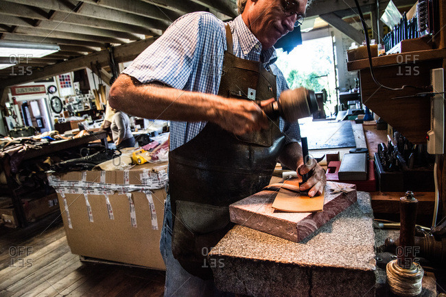 Crozet, Virginia - February 8, 2000: Chuck Pinnell stamping a piece of leather