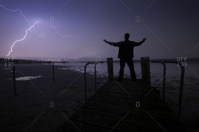 Mature man standing on jetty during a thunderstorm