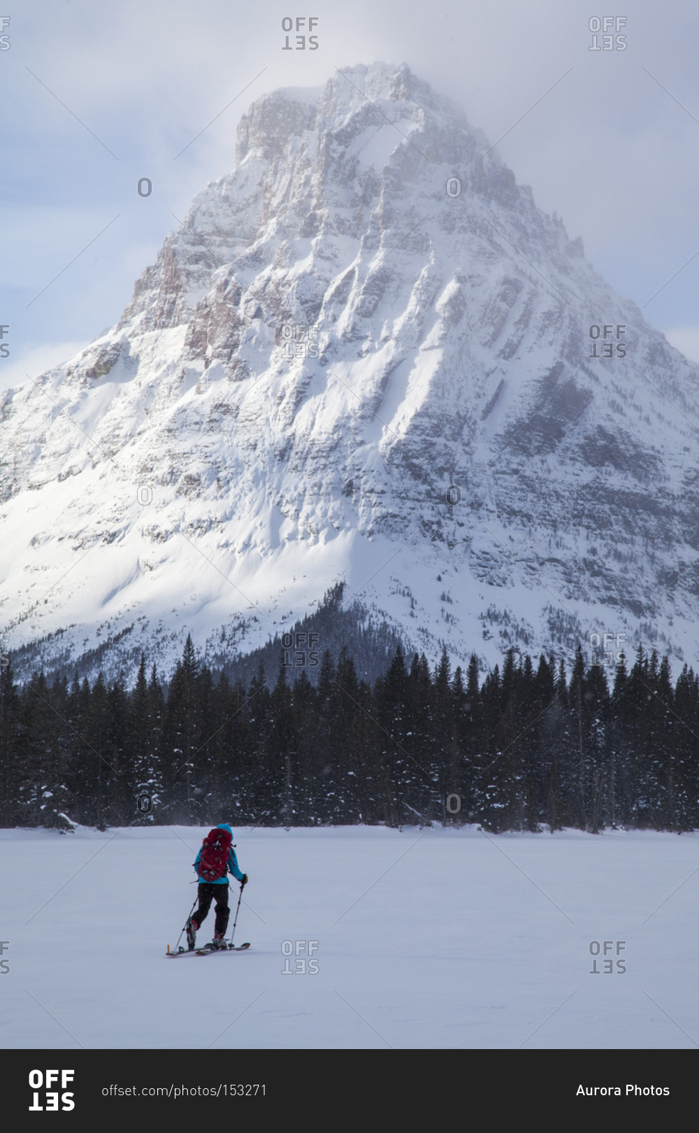 A woman skiing on Two Medicine Lake in front of Sinopah Mountain in Glacier National Park, Montana
