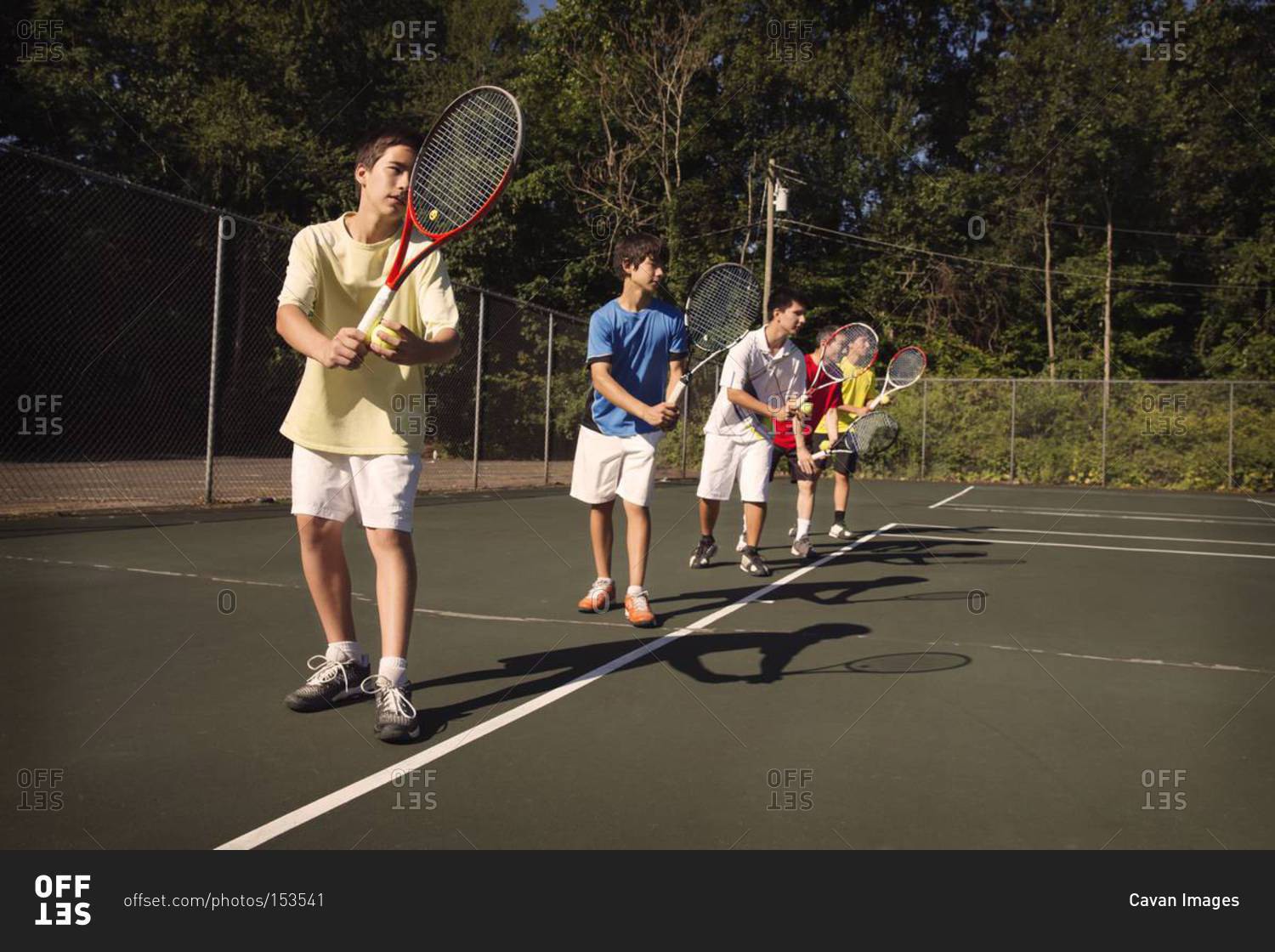 Boys on tennis court about to serve