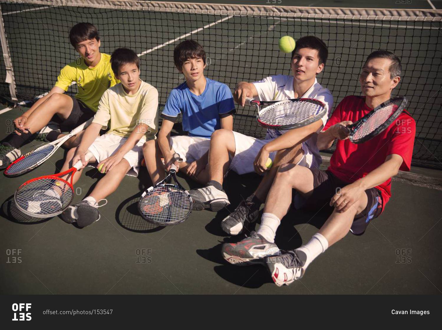 Boys and man resting at tennis net