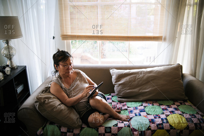 Woman on loveseat listening to tablet