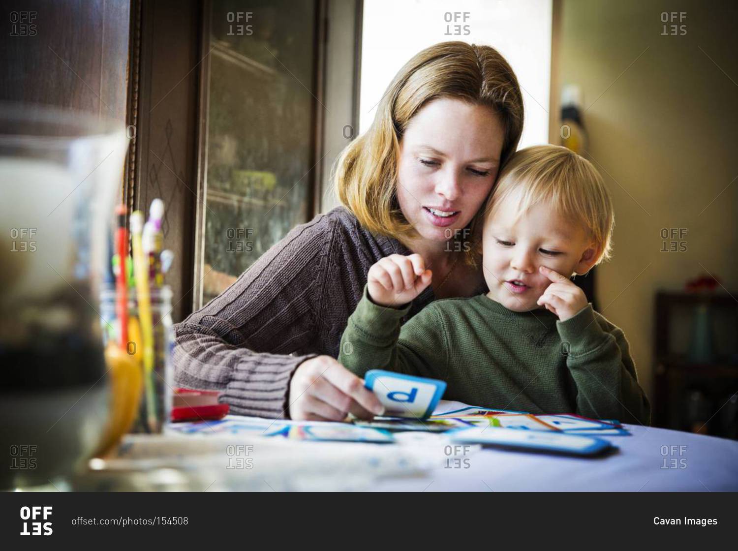 Woman showing alphabet flash cards to her son