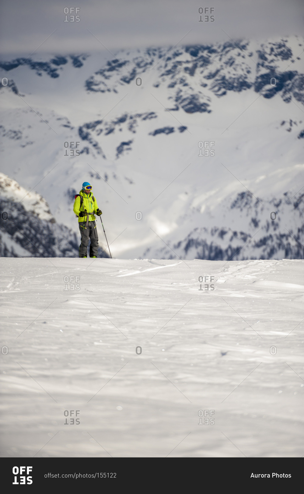 Skier stands on the edge of a steep slope in Devero Valley with snowy mountains in background on a cloudy day Baceno, Piemonte, Ossola
