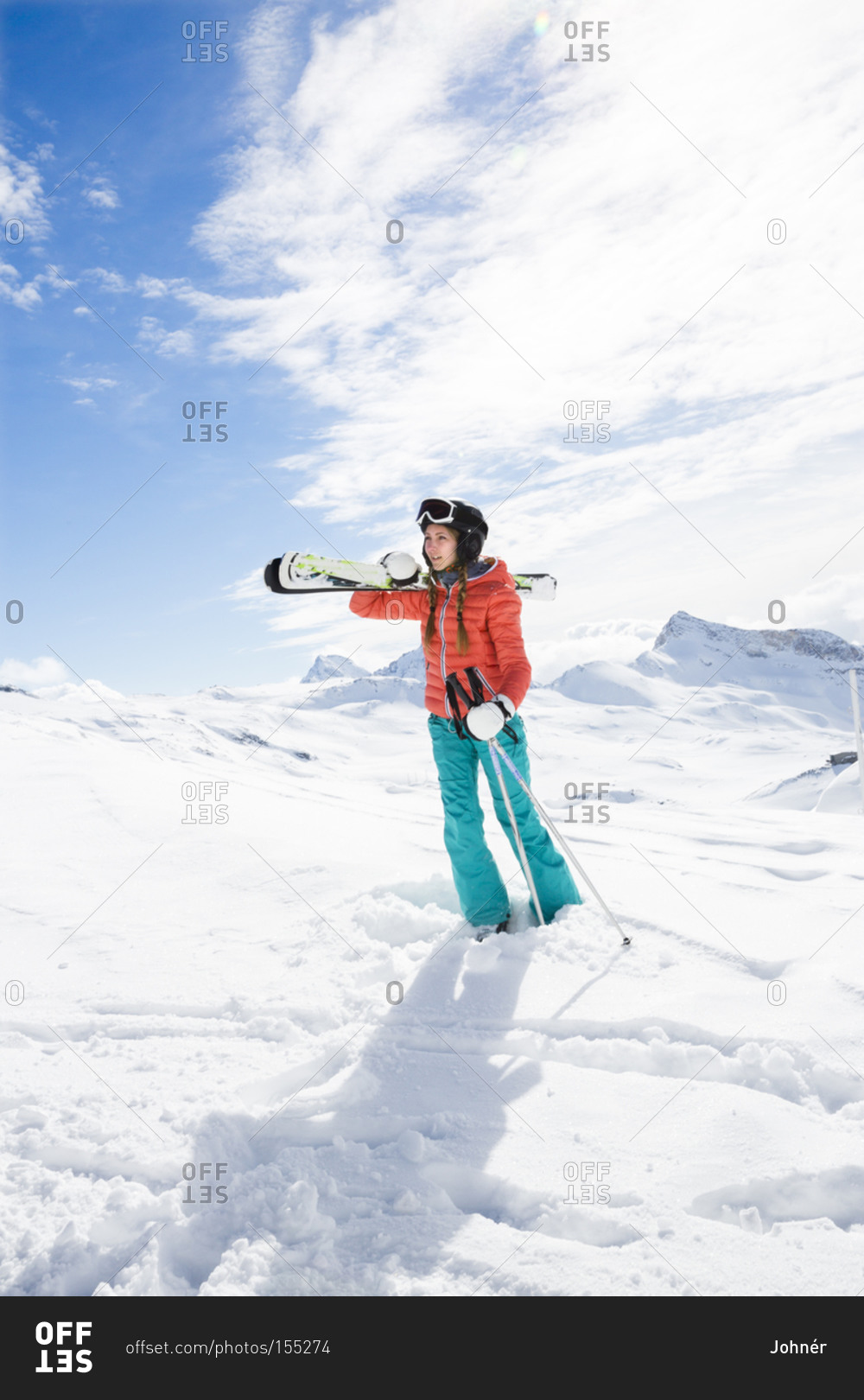 Woman carrying skis and poles stock photo - OFFSET