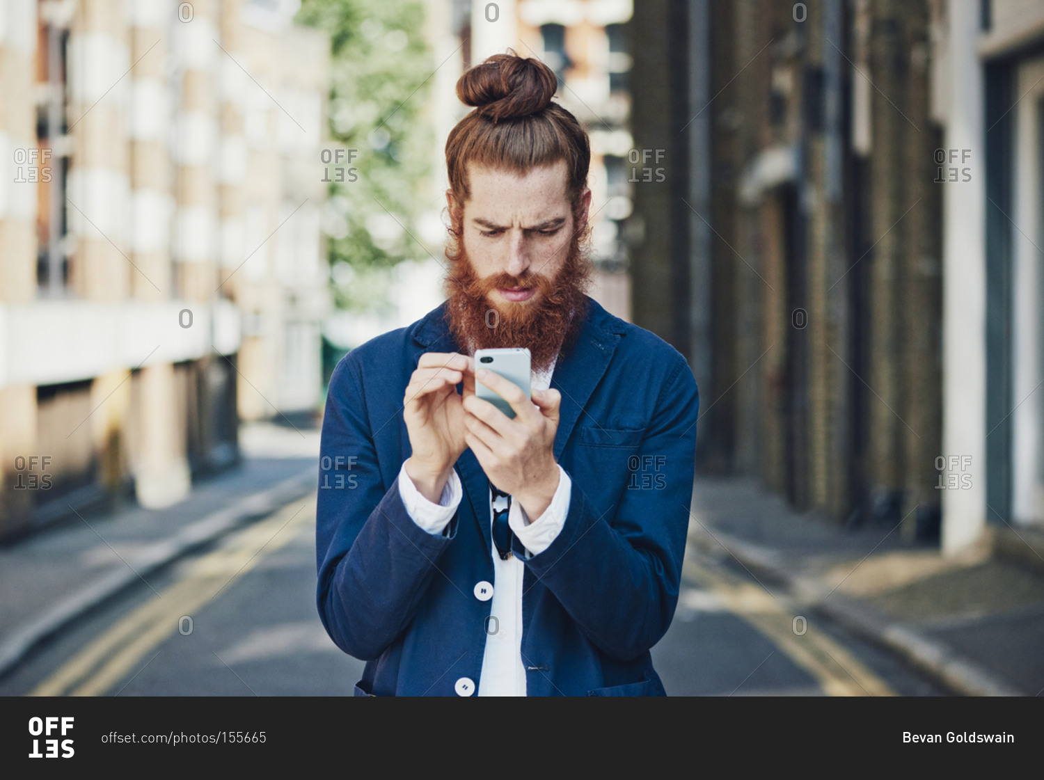 Man in sports coat in street looking at phone