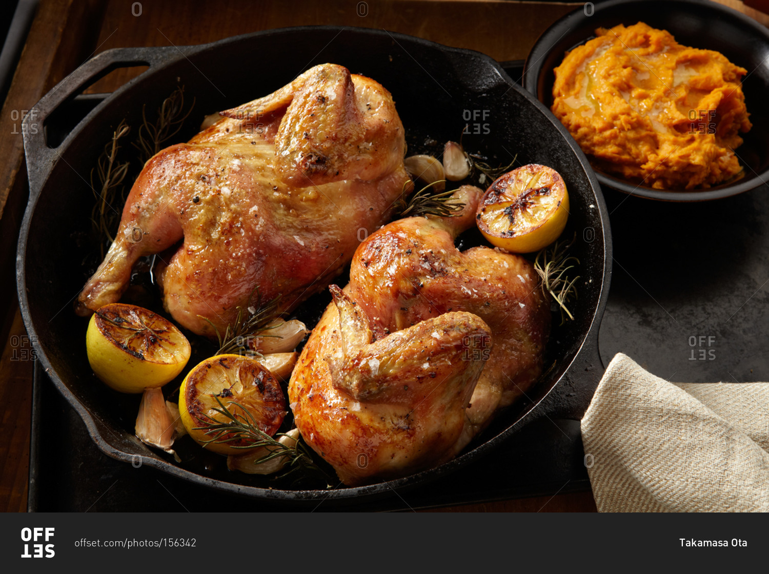 Halved chicken roasting in a cast-iron pan