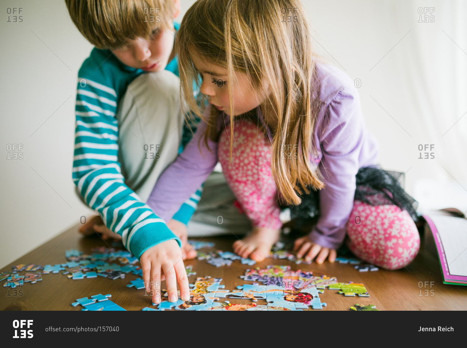 Children putting a jigsaw puzzle together stock photo - OFFSET