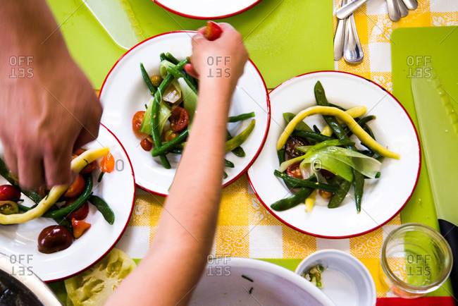 People preparing a green bean and tomato salad