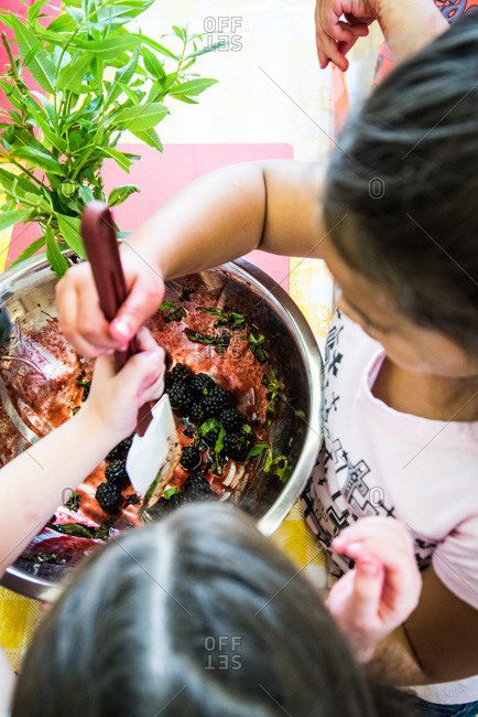 Children making blackberry dessert with green leaves