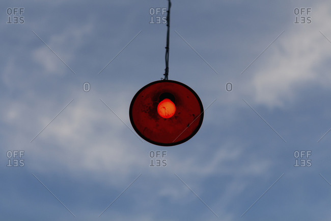 Low angle view of lamp hanging against cloudy sky