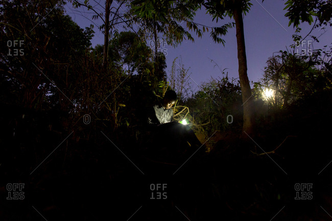 Thyolo, Malawi - April 29, 2013: A young boy orphaned by AIDS reads outside with a flashlight