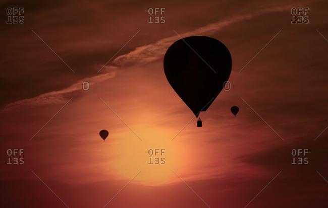 Silhouettes of three air balloons in front of red evening sky
