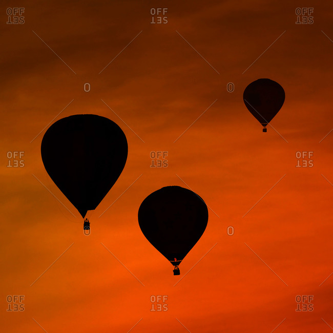 Silhouettes of three air balloons in front of red evening sky