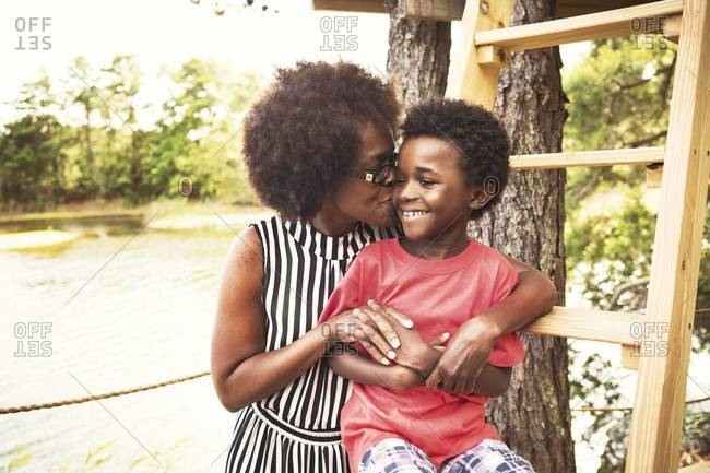 Older Woman Kissing Young Boy On Tree House Ladder Stock Photo OFFSET