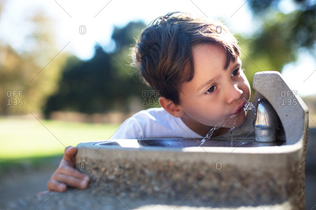 Portrait of a thirsty boy at a drinking fountain