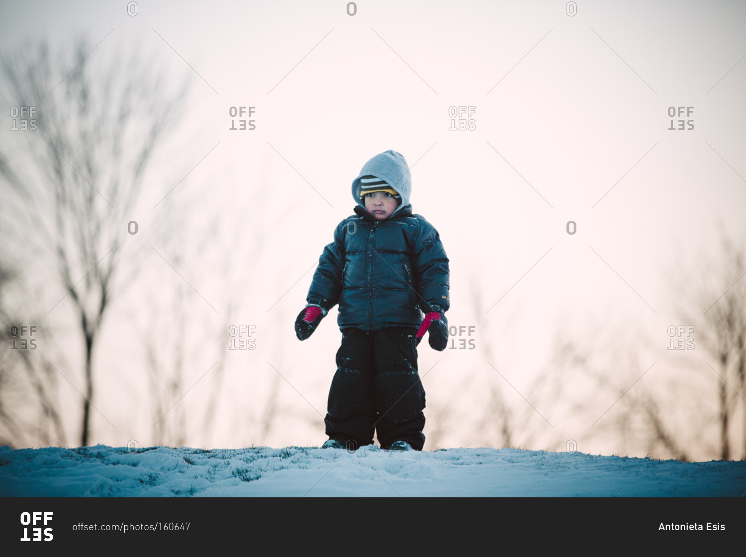 Boy standing on snowy hilltop