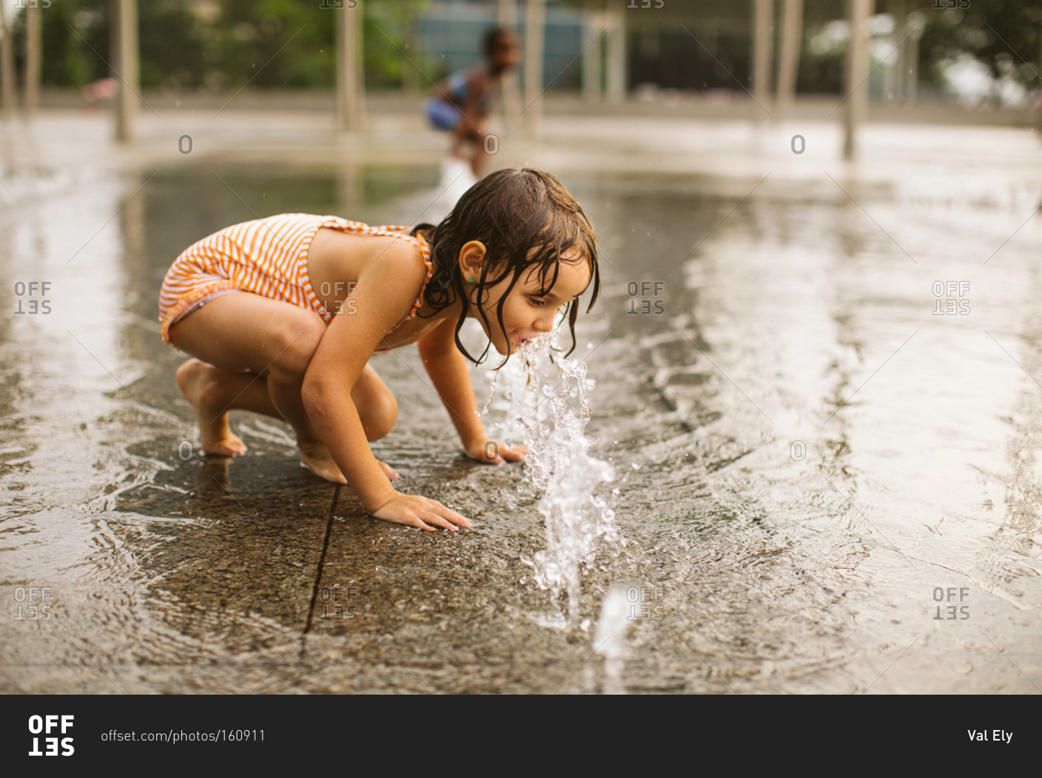 Girl drinking from jets in fountain