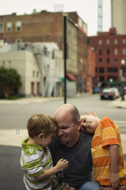 Man hugging two boys in city street