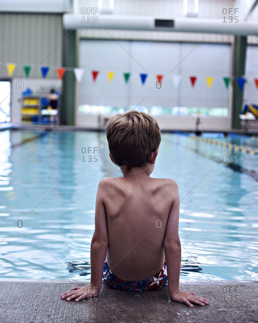 Boy sitting at edge of indoor pool